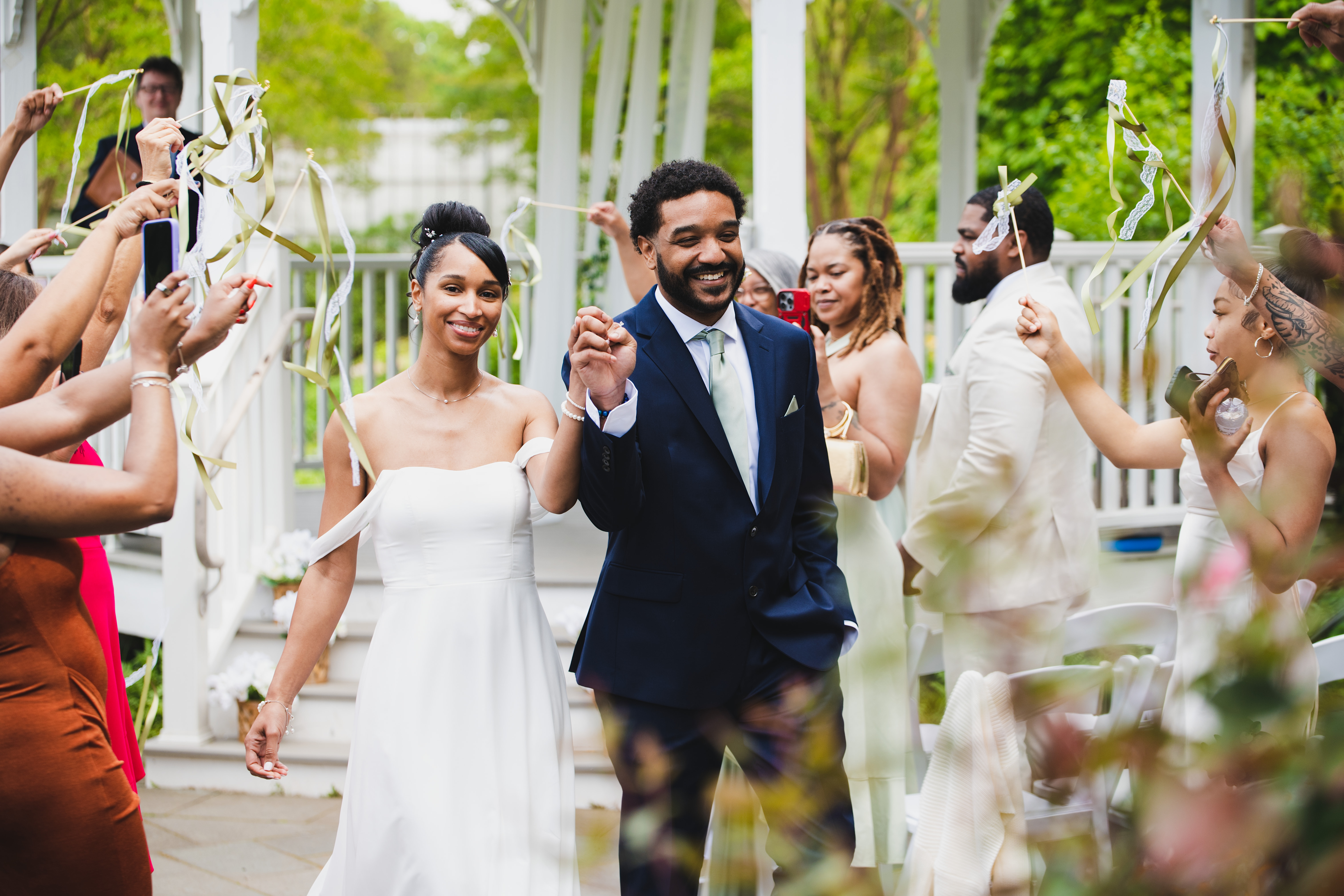 Guests celebrating with ribbons as the couple walks down the aisle